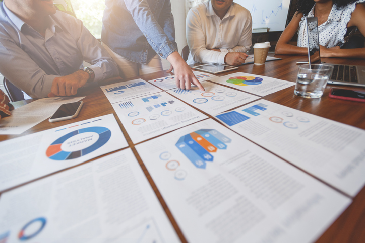 Paperwork and hands on a board room table at a business presentation or seminar.