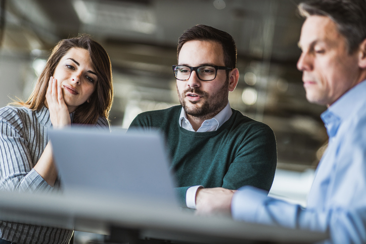 Young couple and real estate agent using laptop on a meeting in the office.