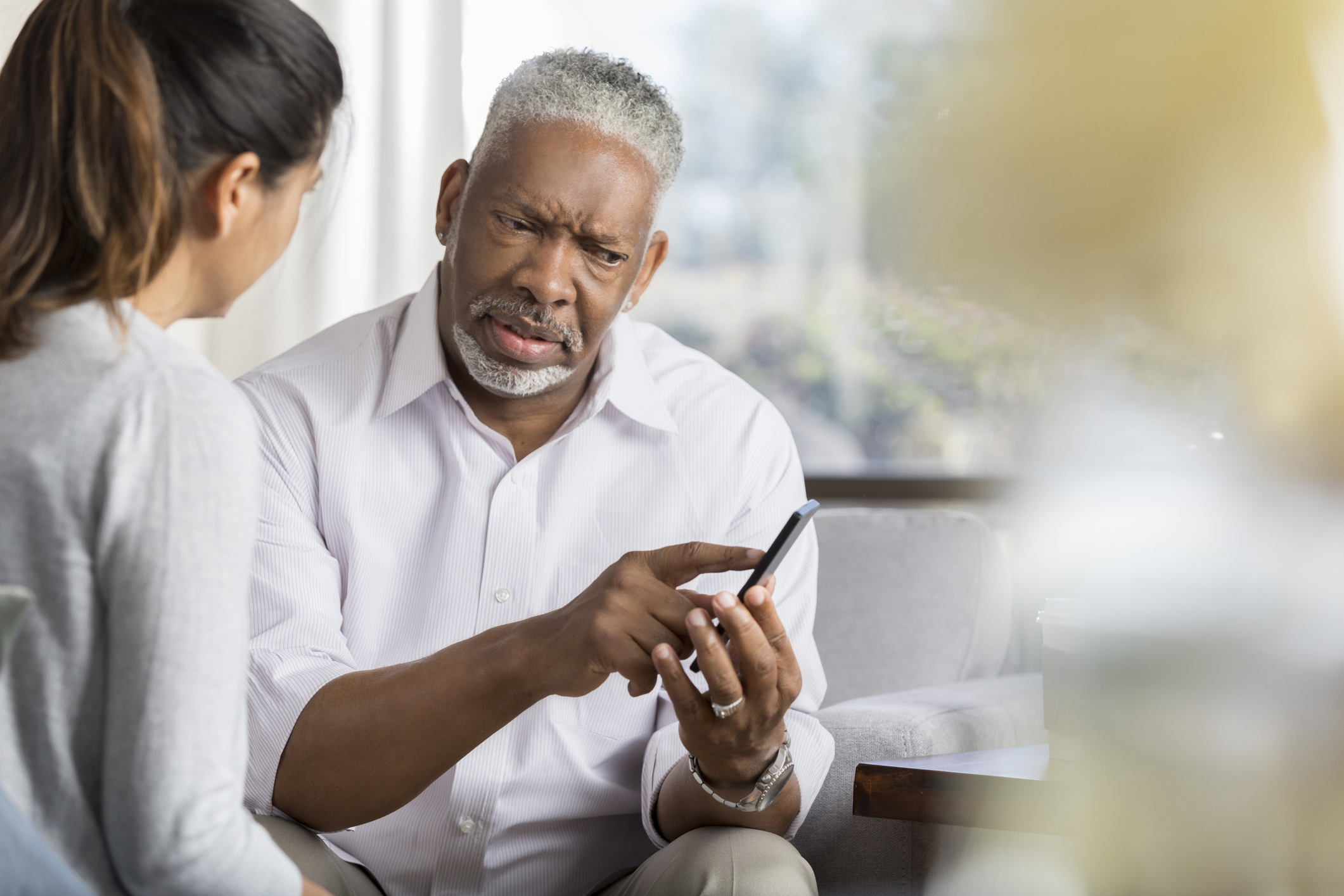 Senior man points at something on smartphone